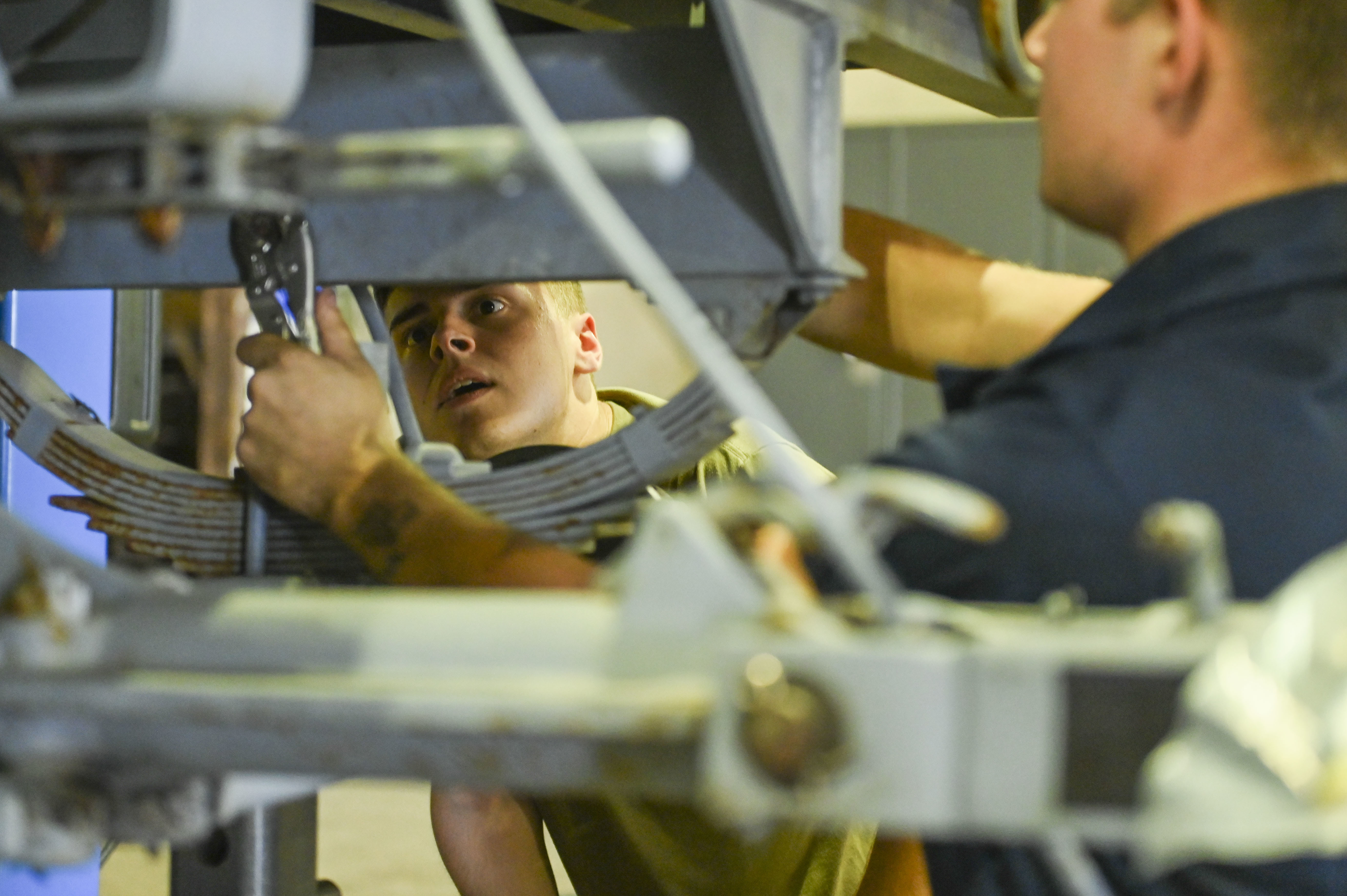 Airman 1st Class Robert Collins watches while Samuel Benson removes a stainless-steel brake line on a munitions trailer. U.S. Air Force photo by Breanna Christopher Volkmar.