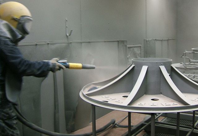 Sand blasting cleans and prepares a pylon mounting plate for coating.