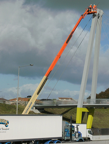 Painters use a high-lift platform to coat a motorway bridge gantry.